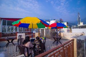 two women sitting on a balcony under an umbrella at Triple One Hostel Tapovan Rishikesh in Rishīkesh