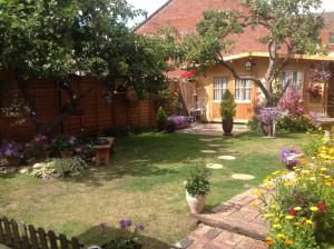a yard with flowers and a house with a fence at Alice Guest house in Cheltenham