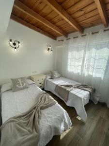 two beds in a room with white walls and wooden floors at Atico el Wiro in Puerto