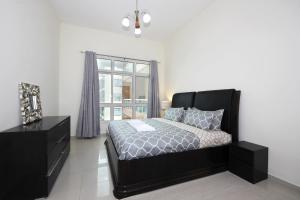 a bedroom with a black bed and a window at Premium Furnished 1 BHK in La Vista 3, Silicon Oasis in Dubai