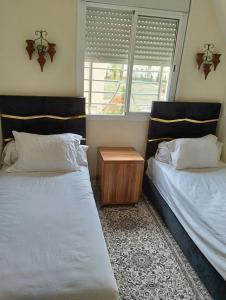 - une chambre avec 2 lits et une table de nuit dans l'établissement Les jardaine d'ifrane, à Ifrane