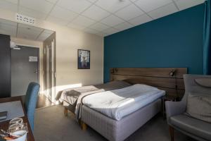 1 dormitorio con cama y pared azul en Hotell Entré Norr, en Umeå