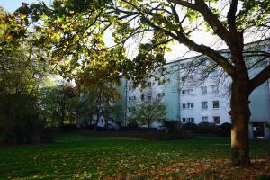 a large white building with a tree in the foreground at unique: cozy - balcony - kitchen - netflix in Bremen