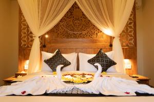 a bedroom with a bed with swans on it at Ubud Inn Cottage by Prasi in Ubud