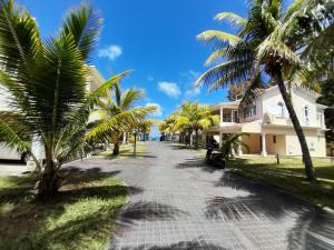 a street with palm trees in front of a house at Le Maho Villa - Beach Front in Port Louis