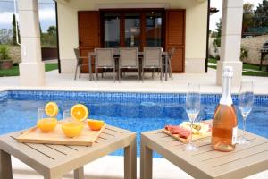 two tables with drinks and fruit on them next to a pool at Villa Julija in Rasopasno