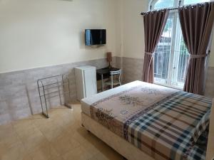 a bedroom with a bed and a table and a window at Ndalem Gorongan Guesthouse in Yogyakarta