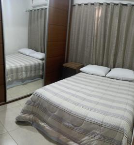 a small bedroom with a bed and a mirror at Apartamento amplo e acolhedor, garagem incluída. in Foz do Iguaçu