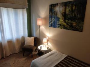um quarto com uma cama, uma cadeira e um candeeiro em Gîte La Renéade 
