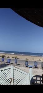 een uitzicht op een strand met stoelen en de oceaan bij Suite BELDI, La Maison des paons in Sidi Kaouki