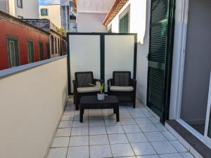 2 Stühle und ein Tisch auf dem Balkon in der Unterkunft Tanoeiros Studios in Funchal