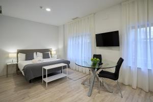 una camera con letto, tavolo e TV di Inés Luna Suites a Salamanca
