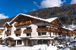 ein großes Gebäude mit Schnee auf dem Dach in der Unterkunft Hotel Europeo Alpine Charme & Wellness in Pinzolo