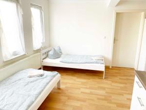 due letti in una stanza con pavimenti in legno e finestre di Fully Equipped Spacious Worker Apartment a Apolda