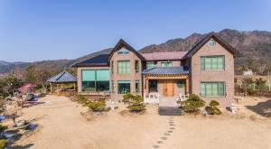 an aerial view of a house with mountains in the background at ChungDam in Pyeongchang