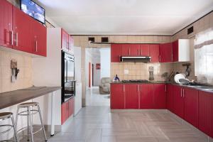 a kitchen with red cabinets and a counter top at 25 Jacaranda Lodge & Backpackers in Pinetown
