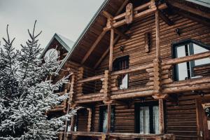 una cabaña de madera en la nieve junto a un árbol en Красна Поляна Family Club Resorts, en Bukovel