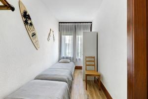 Cette chambre comprend 3 lits et un fauteuil en bois. dans l'établissement Casa de Praia Tróia, à Tróia