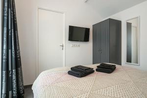 a bedroom with a bed with two black towels on it at Hello Zeeland - Vakantiehuis Wijngaardstraat 12 in Domburg