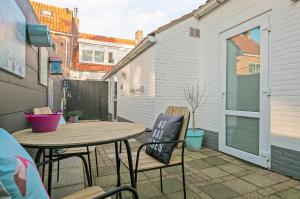 a patio with a wooden table and chairs and a building at Hello Zeeland - Vakantiehuis Wijngaardstraat 12 in Domburg