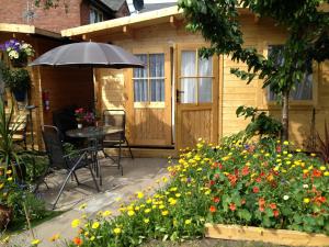 un patio con sombrilla, mesa y flores en Alice Guest house, en Cheltenham