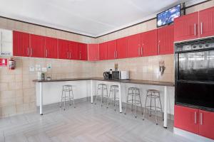 a kitchen with red cabinets and bar stools at 25 Jacaranda Lodge & Backpackers in Pinetown +10 photos