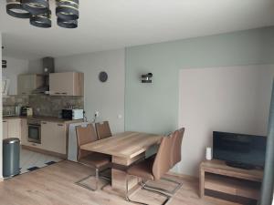 uma cozinha com uma mesa e cadeiras de madeira e uma televisão em City Corner Thermal em Mosonmagyaróvár