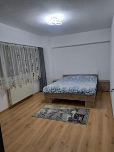 a bedroom with a bed and a rug on a wooden floor at Relax 2 Central Apartment in Bacău