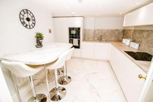 a white kitchen with a bar and a clock on the wall at Spacious 2 bed city centre apartment with parking in Norwich