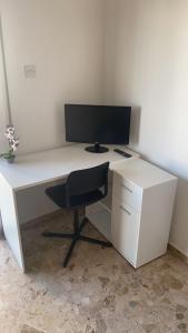 una scrivania bianca con monitor per computer e sedia di Luxury City Rooms a Larnaka