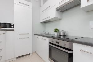 a white kitchen with white cabinets and a stove at Warsaw Young City Apartment by Renters in Warszawa