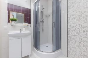 a white bathroom with a shower and a sink at Warsaw Young City Apartment by Renters in Warszawa