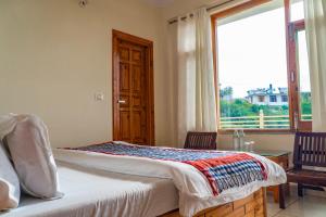 a bedroom with a bed and a large window at Jot Eco Boutique Stays in Dharamshala
