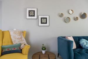 uma sala de estar com uma cadeira amarela e um sofá azul em Six Apartments by Caleta Homes em Málaga