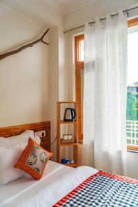 a bedroom with a bed and a window at Jot Eco Boutique Stays in Dharamshala