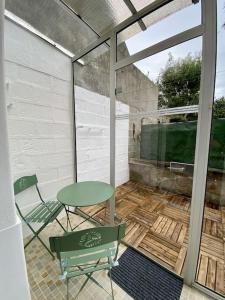 a patio with a green table and chairs on a porch at Ty Matelot by Póm - Proche centre-ville in Lorient