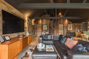ein Wohnzimmer mit einem Ledersofa und einem Flachbild-TV in der Unterkunft Lark Rise by Bloom Stays in Camber