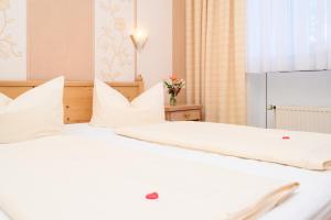 a white bed with white pillows and a window at Landhaus Nienhagen in Ostseebad Nienhagen