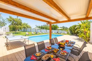 een maaltijd op een tafel op een patio met een zwembad bij Villa Valentina by Algarve Vacation in Almancil