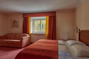 a bedroom with a bed and a chair and a window at Hotel Donauhof in Deggendorf