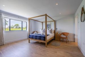 1 dormitorio con cama con dosel y ventana en The Grove - Converted Cattle Barn, en Malmesbury