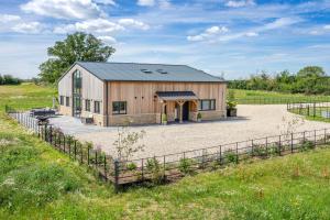 a barn with a fence around it in a field at The Grove - Converted Cattle Barn in Malmesbury