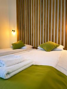 Una gran cama blanca con almohadas verdes. en Pensiunea AN de AN Remeti en Remeţi
