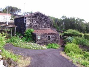 un viejo edificio de piedra con flores delante en Holiday home in Praínha, Pico, Azores, en Prainha de Cima