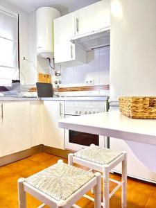 uma cozinha com armários brancos e uma mesa e dois bancos em Apartamento Puerta Cerrada em Écija