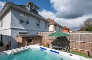 a house with a swimming pool with an umbrella at 1 Min to Beach, 8 Guests, Garden, Snug, Parking - Azure House in Bournemouth