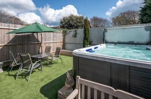 un patio trasero con bañera de hidromasaje, mesa y sillas en 1 Min to Beach, 8 Guests, Garden, Snug, Parking - Azure House en Bournemouth