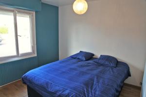 a bedroom with a bed with blue sheets and a window at Mer, belle vue, emplacement parfait, fonctionnel in Penmarch