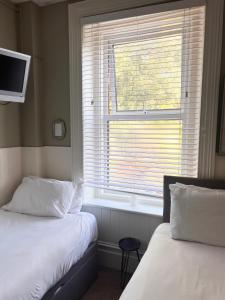 a bedroom with two beds and a window with a television at The Boho - 4 min walk to beach & town in Bournemouth