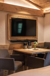 a room with a table with chairs and a large tv at Bärenbach - Almhütte Saalbach in Saalbach Hinterglemm